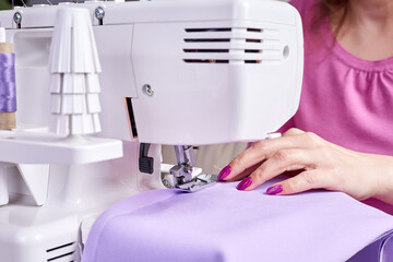 Wall Mural - Woman overstitches a dress on an overlocker