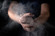 © Konstiantyn Zapylaie - A man claps his hands with scattering flour against a dark background. Culinary theme.