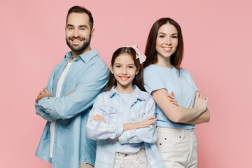 Canvas Print - Young cheerful fun parents mom dad with child kid daughter teen girl in blue clothes hold hands crossed folded isolated on plain pastel light pink background. Family day parenthood childhood concept.