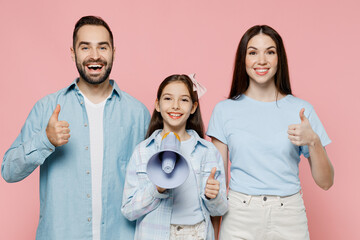 Wall Mural - Young smiling parents mom dad with child kid daughter teen girl in blue clothes hold scream in megaphone announces discounts sale Hurry up show thumb up isolated on plain pastel light pink background