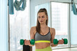 © RomanR - young sports trained woman doing exercises in the gym with extra weight and sports equipment.