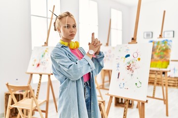 Canvas Print - Young caucasian girl at art studio holding symbolic gun with hand gesture, playing killing shooting weapons, angry face