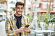© Krakenimages.com - Handsome hispanic man smiling happy and confident at the city using smartphone