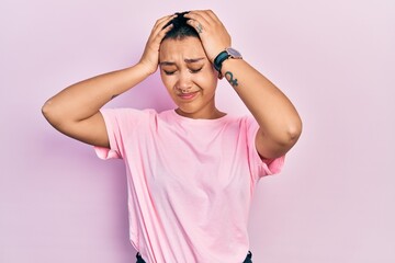 Poster - Beautiful hispanic woman with short hair wearing casual pink t shirt suffering from headache desperate and stressed because pain and migraine. hands on head.