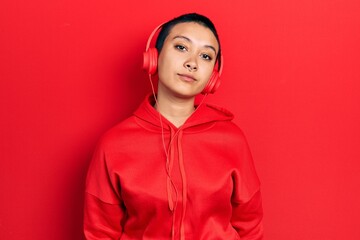 Canvas Print - Beautiful hispanic woman with short hair listening to music using headphones relaxed with serious expression on face. simple and natural looking at the camera.