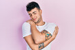 © Krakenimages.com - Young hispanic man wearing casual white t shirt hugging oneself happy and positive, smiling confident. self love and self care