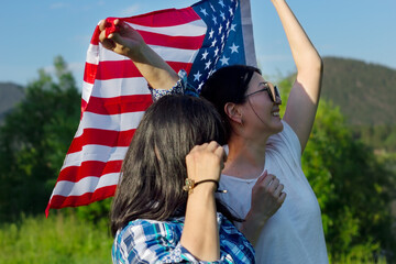 Two smiling asian woman outdoors waving USA flag, celebration of patriotic american national holiday 4th of july independence day