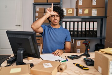 Poster - Hispanic man with curly hair working at small business ecommerce making fun of people with fingers on forehead doing loser gesture mocking and insulting.