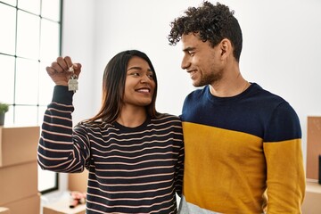 Poster - Young latin couple smiling happy and hugging holding key of new home.