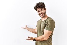 Hispanic Man Standing Over Isolated White Background Inviting To Enter Smiling Natural With Open Hand