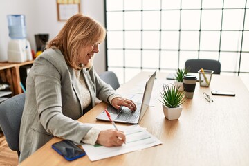 Wall Mural - Middle age businesswoman smiling happy working at the office.