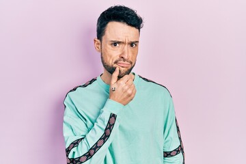 Poster - Young hispanic man wearing casual clothes serious face thinking about question with hand on chin, thoughtful about confusing idea