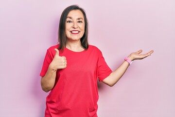 Canvas Print - Middle age hispanic woman wearing casual clothes showing palm hand and doing ok gesture with thumbs up, smiling happy and cheerful