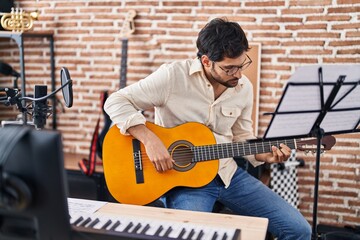 Wall Mural - Young hispanic man musician playing classical guitar at music studio