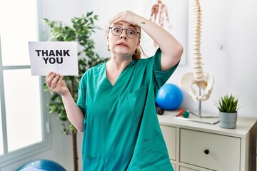 Poster - Young redhead physiotherapist woman working at pain recovery clinic holding thank you banner stressed and frustrated with hand on head, surprised and angry face