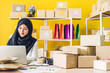 © Art_Photo - Portrait of beautiful muslim owner asian woman freelancer sme business online shopping working and look at camara holding parcel box on table at home - Business online shipping and delivery