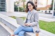 © Krakenimages.com - Young hispanic woman executive using laptop sitting on bench at street