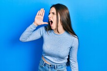 Young Brunette Teenager Wearing Casual Sweater Shouting And Screaming Loud To Side With Hand On Mouth. Communication Concept.