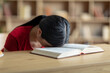 © Prostock-studio - Boring tired unhappy upset teen asian girl lies on book in room or library interior