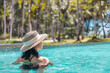 © TripleP Studio - Happy asian woman in red swimsuit and a straw hat relaxing in swimming pool looking at view by the pool at Koh Mak, Phangnga, Thailand. relax and travel concept. Comfort resort summer vacation