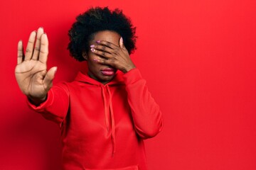 Wall Mural - Young african american woman wearing casual sweatshirt covering eyes with hands and doing stop gesture with sad and fear expression. embarrassed and negative concept.