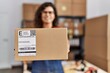 © Krakenimages.com - Young latin woman ecommerce business worker holding package at office