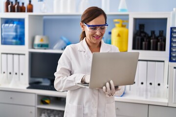 Poster - Middle age woman wearing scientist uniform using laptop at laboratory