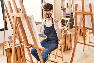 Poster - Hispanic man with beard at art studio surprised with an idea or question pointing finger with happy face, number one