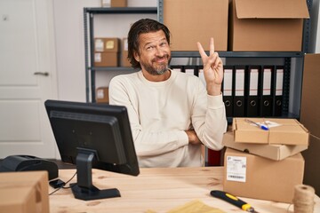 Sticker - Handsome middle age man working at small business ecommerce smiling with happy face winking at the camera doing victory sign. number two.