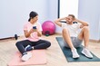 © Krakenimages.com - Man and woman couple smiling confident training abs exercise using smartphone at sport center