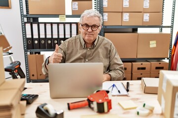 Sticker - Senior caucasian man working at small business ecommerce with laptop doing happy thumbs up gesture with hand. approving expression looking at the camera showing success.