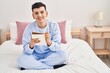 © Krakenimages.com - Young non binary man writing on notebook sitting on bed