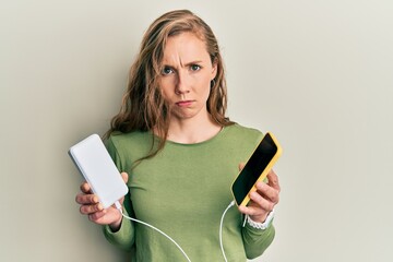 Canvas Print - Young blonde woman charging smartphones skeptic and nervous, frowning upset because of problem. negative person.