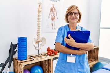 Sticker - Middle age blonde woman wearing physiotherapist uniform holding checklist at clinic