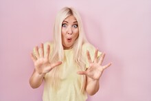 Caucasian Woman Standing Over Pink Background Afraid And Terrified With Fear Expression Stop Gesture With Hands, Shouting In Shock. Panic Concept.