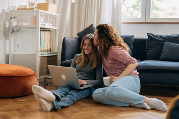 mother and daughter feeling relaxed sitting in living room and using laptop computer