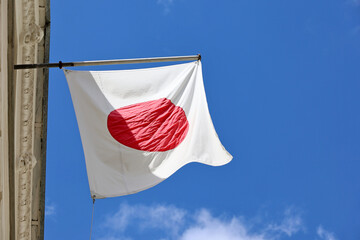 Wall Mural - Japanese flag on the building top on blue sky background, authority of Japan