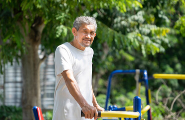 happy senior man doing exercise at outdoor fitness equipment in the park, concept old people lifestyle, health care in elderly people