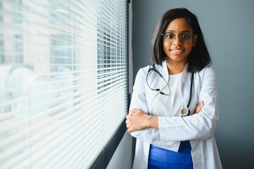 Smiling young adult indian female doctor wear white coat in medical clinic office. Happy beautiful health care india professional medic physician, therapist, headshot portrait