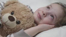 Little Child Girl Hugging Teddy Bear Lying Bedroom Bed. Kid Falls Asleep Bed With Favorite Doll. Happy Family. Cheerful Smiling Daughter. Chidhood Dream Head Pillow Trying Asleep Embrace Teddy Bear.