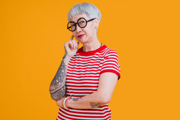 senior asian female grey hair fashioned cloth with tattoo arm standing hand gesture with positive co