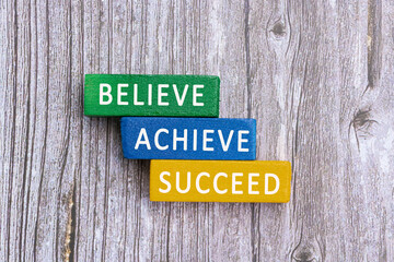 Wall Mural - Motivational quotes on wooden block cube - Believe, achieve, succeed.