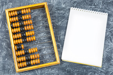 old antique wooden abacus and a notebook with a blank page for writing on a black (dark) background.