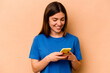 © Asier - Young caucasian woman holding mobile phone isolated on beige background