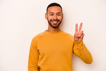 Wall Mural - Young hispanic man isolated on white background showing victory sign and smiling broadly.