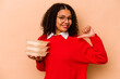 Young African American woman holding tupperware isolated on beige background feels proud and self confident, example to follow.