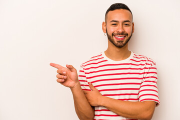 Wall Mural - Young hispanic man isolated on white background smiling cheerfully pointing with forefinger away.