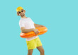 © Studio Romantic - Funny young man in sun hat and sunglasses with lifebuoy excited about summertime vacations. Smiling teen guy ready for great summer holidays or adventures. Tourism and travel concept.