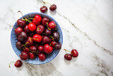 Fresh sweet cherries bowl on marble background. Top view with copy space