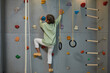 Leinwandbild Motiv Full length portrait of active black child climbing wall on home sports set, copy space